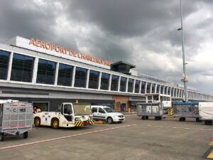 Clădirea terminalului 1 al aeroportului Bruxelles Charleroi, văzută de pe platformă, cu vehicule de handling și cărucioare de bagaje