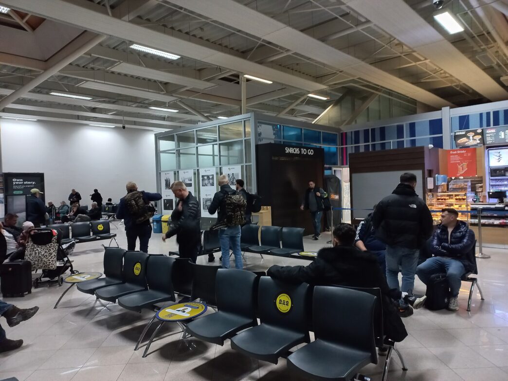 Pasageri care așteaptă pe scaune în zona de îmbarcare a Aeroportului Internațional Sibiu