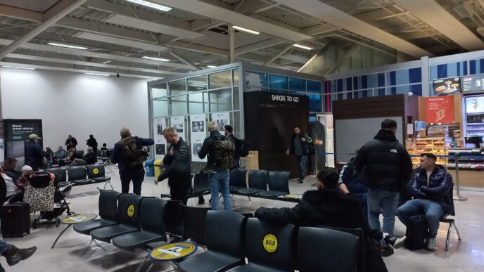 Pasageri care așteaptă pe scaune în zona de îmbarcare a Aeroportului Internațional Sibiu