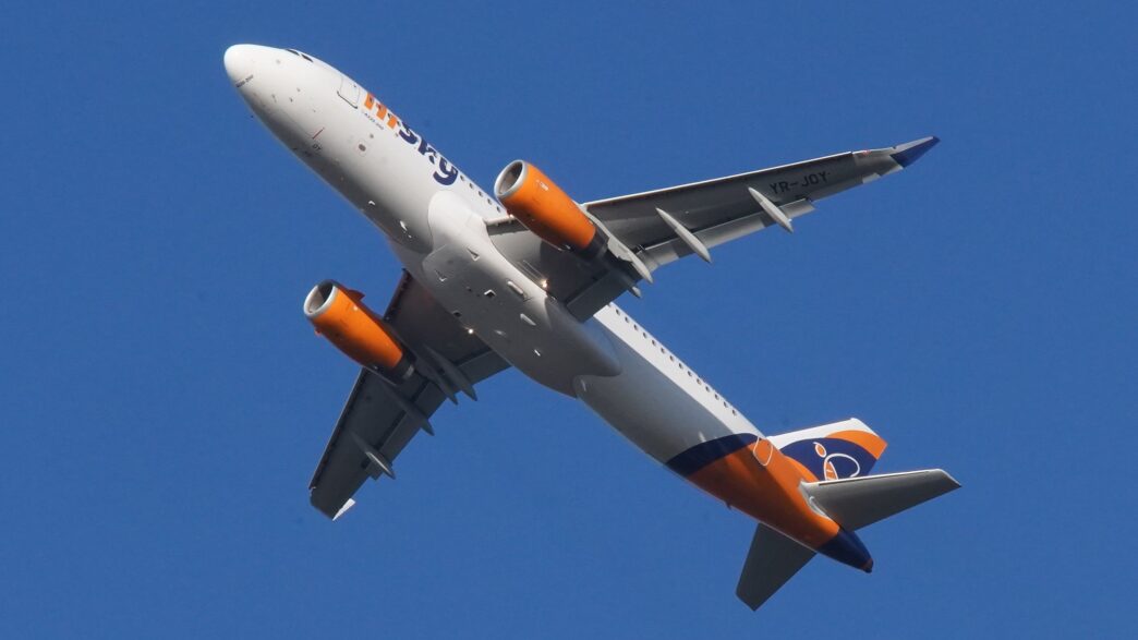 Avion Airbus A320 în culorile HiSky, fotografiat de jos în timpul zborului, pe cer albastru senin