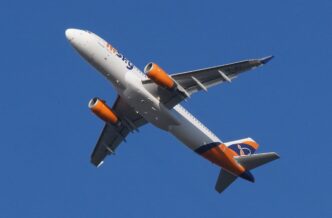 Avion Airbus A320 în culorile HiSky, fotografiat de jos în timpul zborului, pe cer albastru senin
