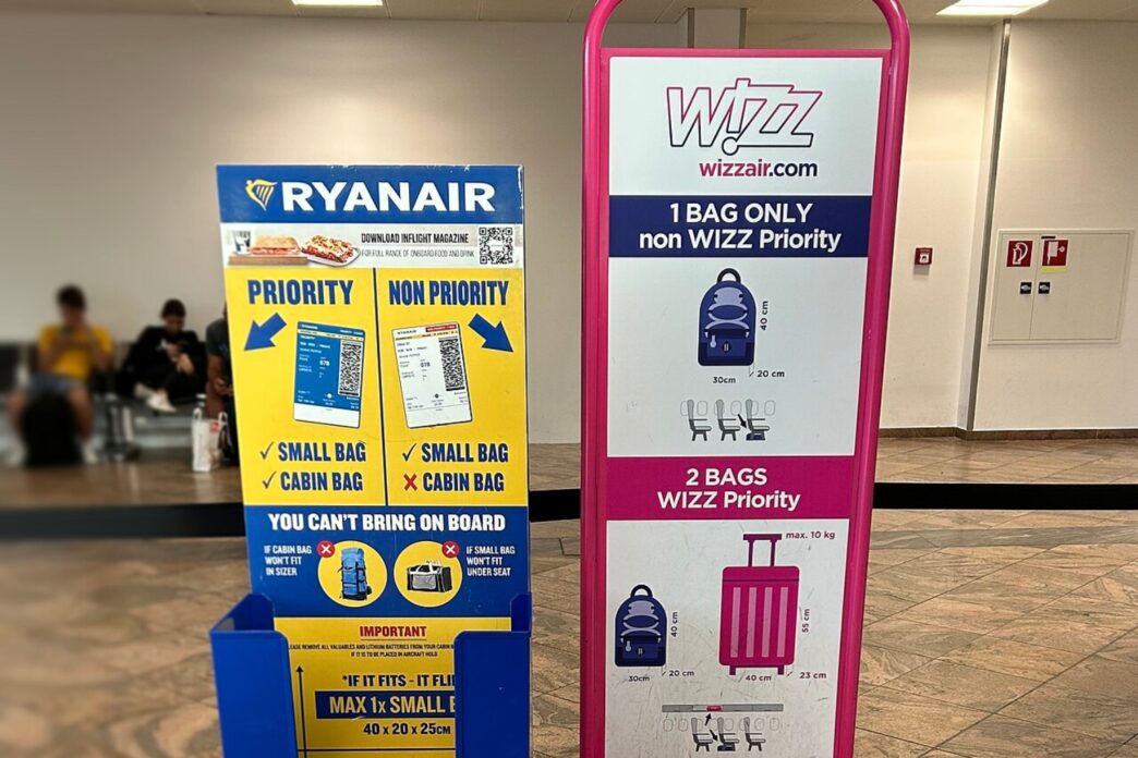Două dispozitive de măsurare a bagajului de mână, Ryanair și Wizz Air, așezate unul lângă altul în holul unui aeroport