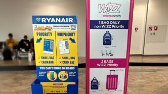 Două dispozitive de măsurare a bagajului de mână, Ryanair și Wizz Air, așezate unul lângă altul în holul unui aeroport