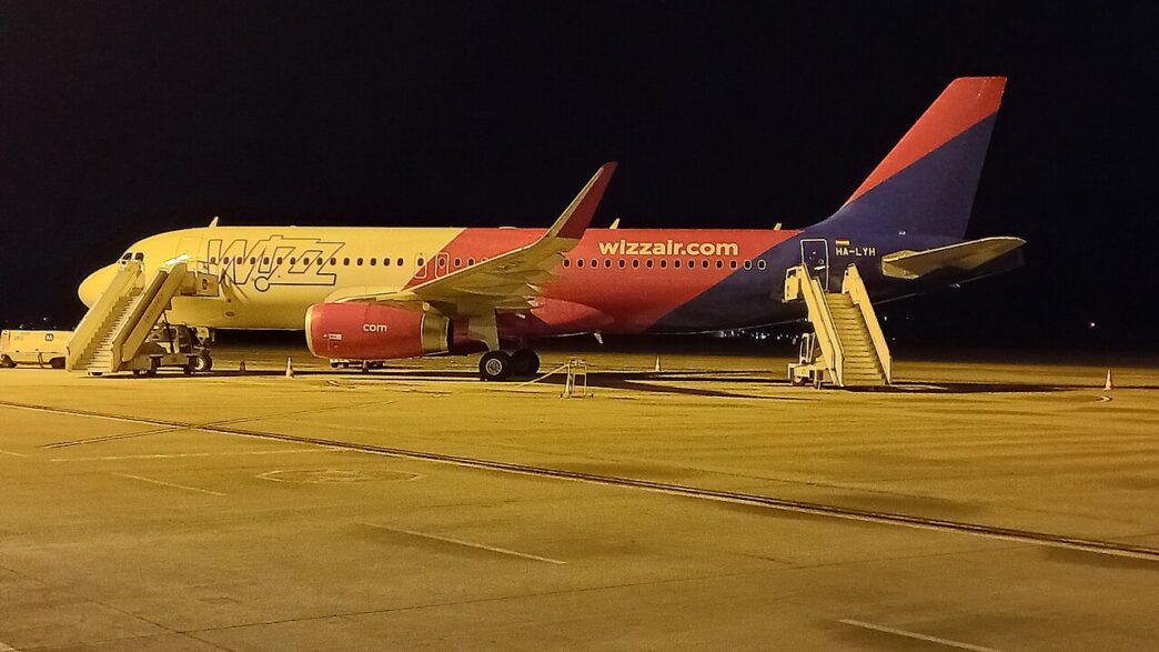 Avion Airbus A320 în culorile Wizz Air, parcat noaptea pe platforma Aeroportului Internațional Sibiu, cu scările de îmbarcare atașate