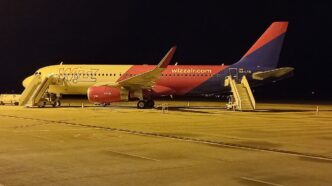 Avion Airbus A320 în culorile Wizz Air, parcat noaptea pe platforma Aeroportului Internațional Sibiu, cu scările de îmbarcare atașate