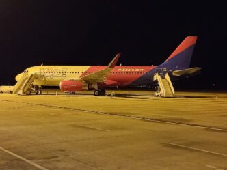 Avion Airbus A320 în culorile Wizz Air, parcat noaptea pe platforma Aeroportului Internațional Sibiu, cu scările de îmbarcare atașate