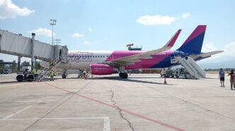 Avion Airbus A320 în culorile Wizz Air pe platformă, cu scări mobile la ușile din față și din spate, personal de sol și câțiva pasageri, într-o zi senină